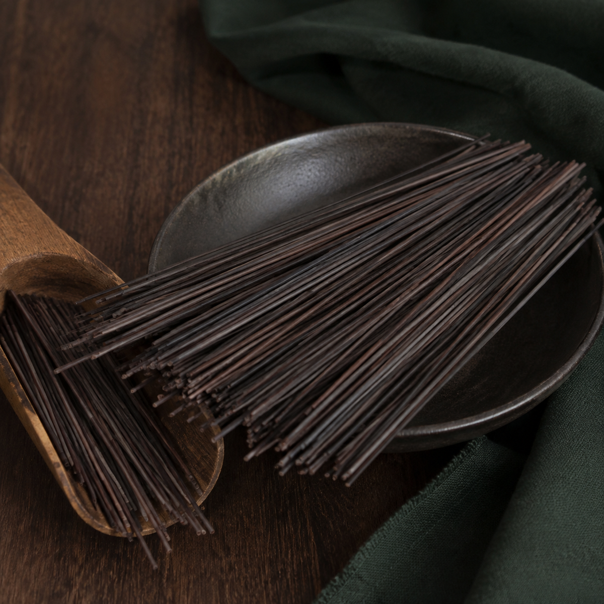 Dry organic black rice noodle strands on dark walnut