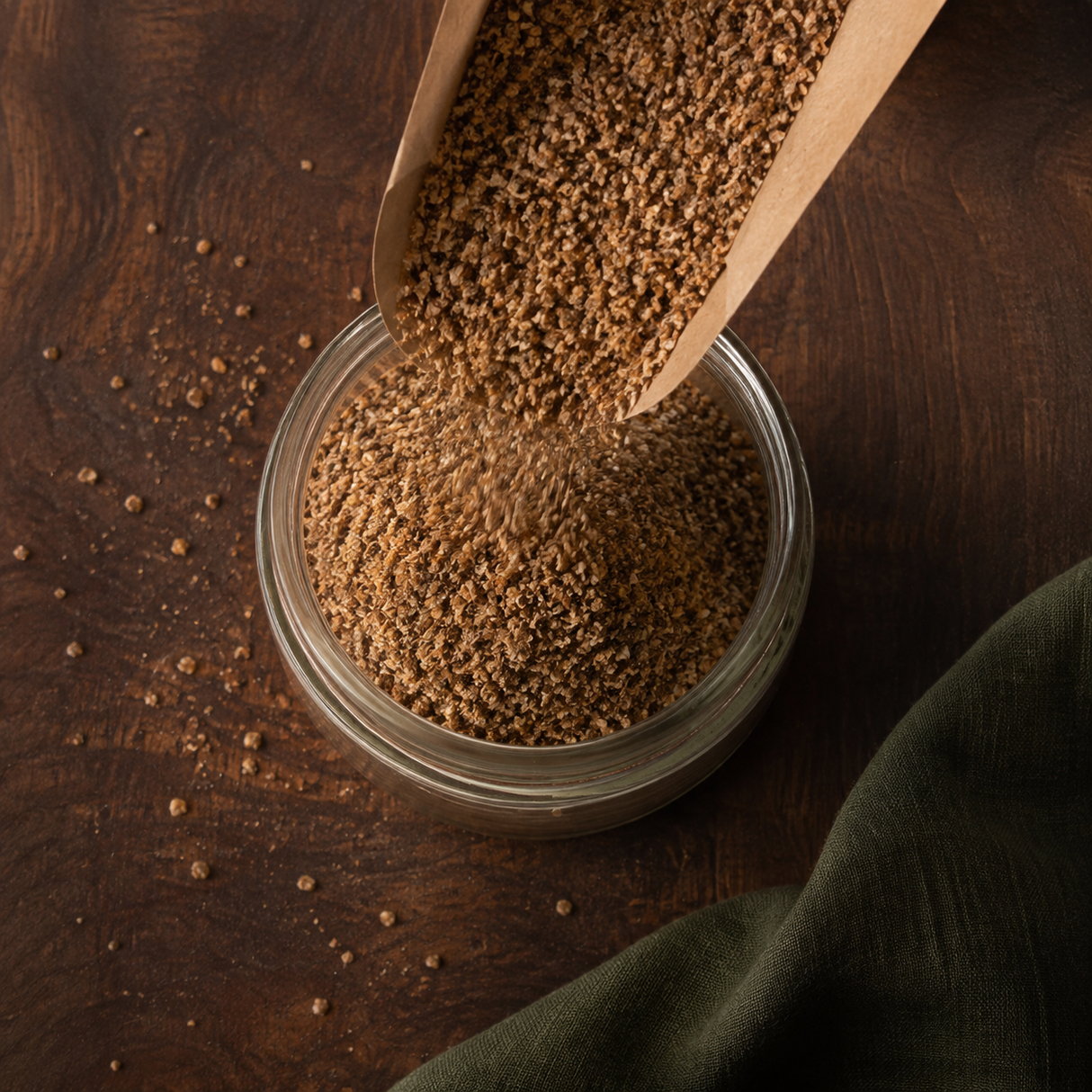 Organic ground brown flaxseed pouring into a pantry jar