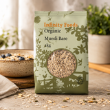 Infinity Foods Organic Muesli Base package on a wooden surface with a bowl of muesli in the background.