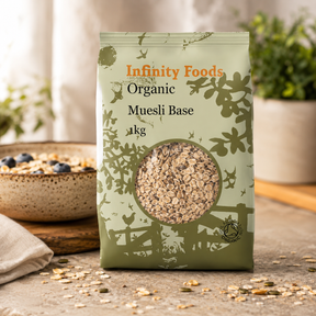 Infinity Foods Organic Muesli Base package on a wooden surface with a bowl of muesli in the background.