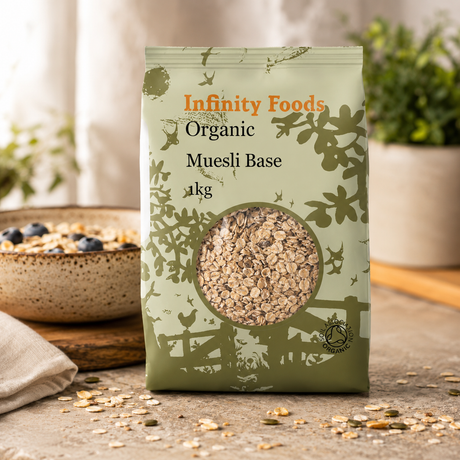 Infinity Foods Organic Muesli Base package on a wooden surface with a bowl of muesli in the background.
