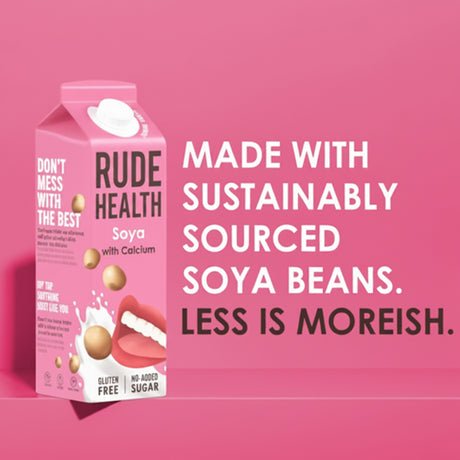 Rude Health soya product packaging on a pink background with text about sustainably sourced soya beans.