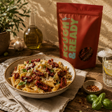 Pasta dish with sun-dried tomatoes on a wooden table next to a 'Rough & Ready' package.