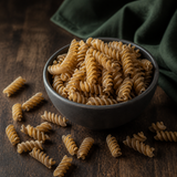 Dry organic brown rice fusilli in a dark bowl