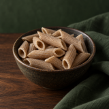 Dry organic buckwheat penne in a dark ceramic bowl