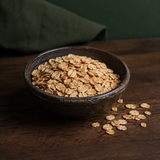 Infinity Foods Organic Muesli Base cereal flakes in a dark ceramic bowl