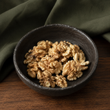 Organic walnut halves in a dark ceramic bowl