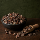 Organic chopped apricots in a black bowl with scoop