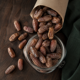 Organic Deglet Nour pitted dates pouring into a pantry jar