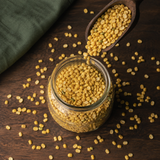 Organic mung dal pouring into a glass pantry jar