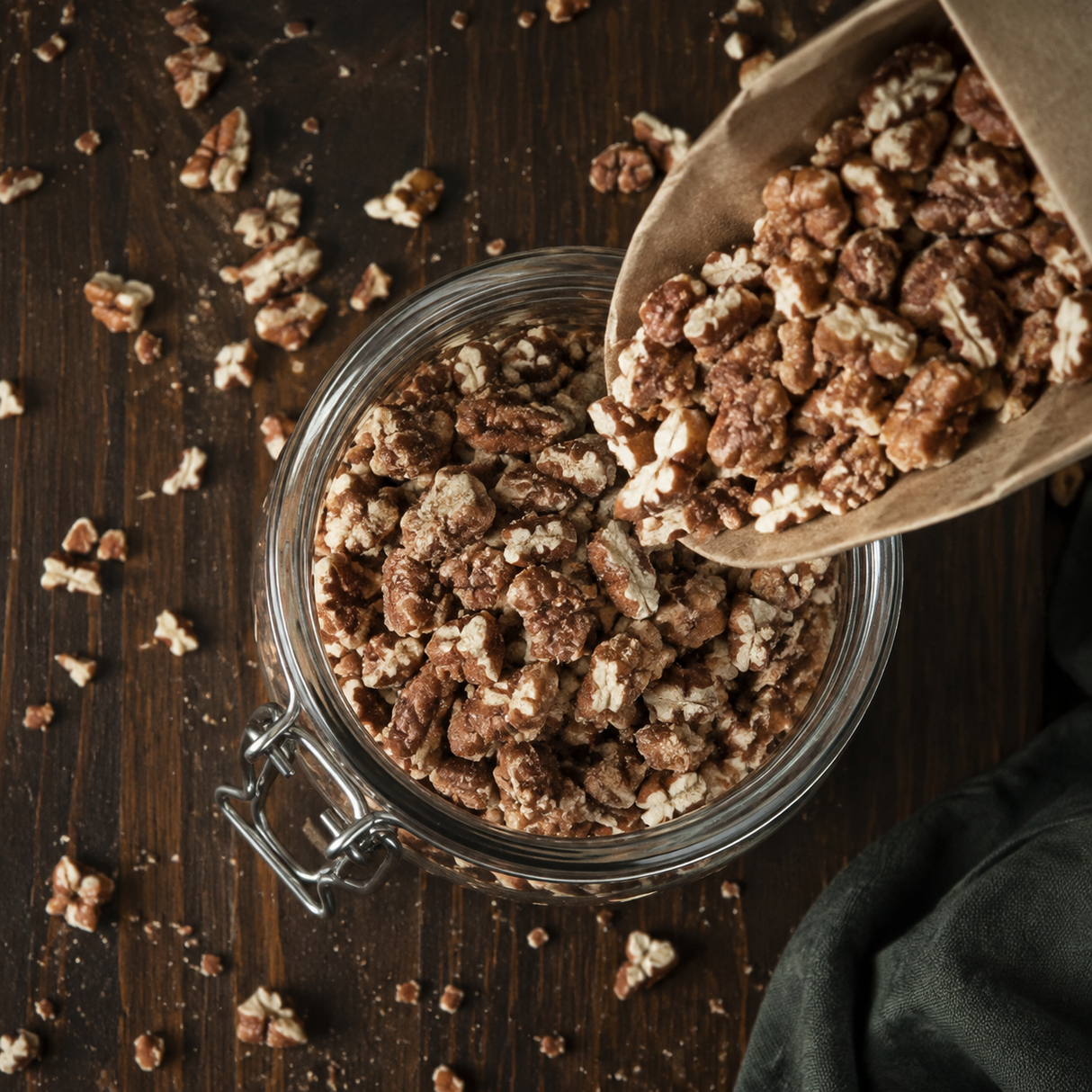Organic pecan pieces pouring into a pantry jar