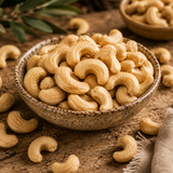 Bowl of cashews on a wooden surface with cashews scattered around