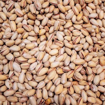 A close-up image of roasted and salted pistachio nuts in shells.